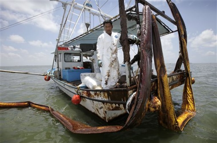 In this photo made Friday, June 11, 2010, Allen Sreiy stands next to oily booms on his shrimp boat as he helps in cleanup operations for the Deepwater Horizon oil spill, in Bay Jimmy near Venice, La. Sreiy's Tyvek suit, worn by hundreds of workers cleaning up oil along the Gulf Coast, protects crews from the crude but it also makes for a sweaty _ and potentially dangerous _ mess as a sweltering heat wave sweeps across the region. (AP Photo/Charlie Neibergall)